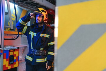 Firefighters man in a protective suit near fire truck. Protection, rescue from danger. Fire station