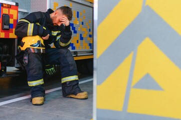 depressed and tired firefighter near fire truck