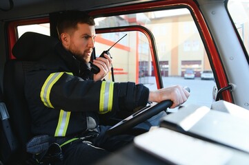 Side view of firefighter in protective uniform driving fire engine