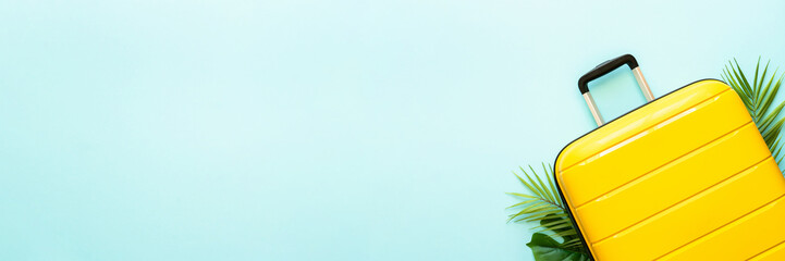 Summer holidays on blue background. Yellow Suitcase and palm leaves. Long banner format.