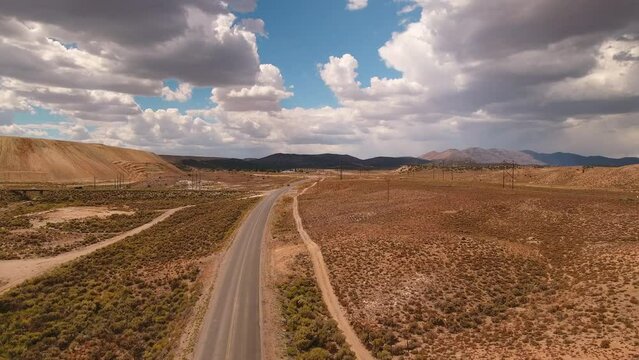 Aerial: Drone Forward Shot Of Pick-Up Trucks Moving On Road In Tranquil Desert Under Cloudy Sky - Ely, Nevada