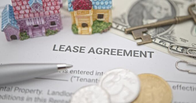 Business legal document concept : Pen, coins, key on a lease agreement form. Lease agreement is a contract between a lessor and a lessee that allow lessee rights to use of a property owned by lessor.