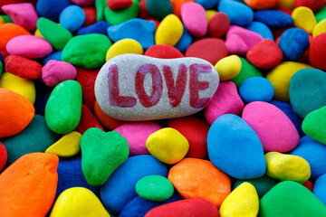 Word Love written on stone among many multi colored stones 