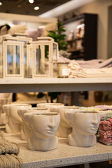 Artistic face-shaped ceramic mugs on display, with soft focus background of a cozy interior decor store