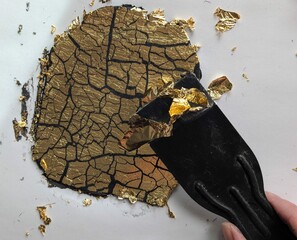 Spatula working with gold leaf on black clay background