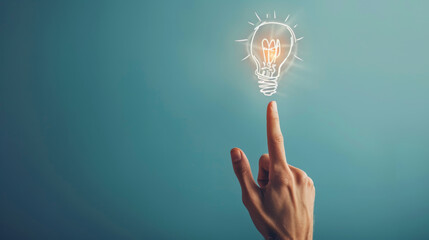 A hand touching a drawn lightbulb symbolizing an idea on a teal background.