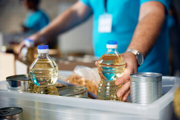 Close up of volunteer packing food into boxes at donation center.