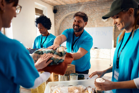 Group of happy volunteers sorting donations while working at charitable foundation.