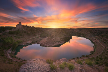 View of a colorful sunset from the Alarcon viewpoint, Cuenca, with the warm clouds reflecting in the Jucar River