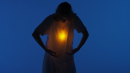 Female dancer performing in the studio. Young woman dancing in dark studio with warm light glowing...