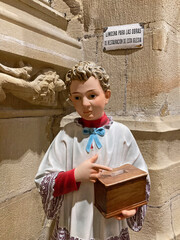 figura de monaguillo con una hucha para pedir limosna en el interior de una iglesia de...
