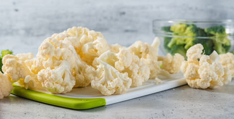 Cauliflower florets, and broccoli florets close-up on a light grey background