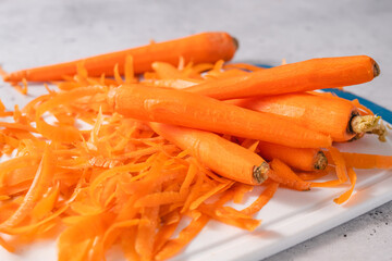 Peeled carrots close-up on a cutting board on a light grey stone background