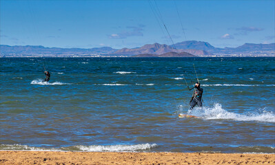 Two kite surfers parallel with each other on the ocean