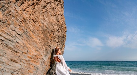 Woman beach white dress flying on Wind. Summer Vacation. A happy woman takes vacation photos to send to friends.