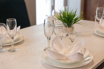 Glasses, plates, napkins served for dinner in restaurant with cozy interior.
