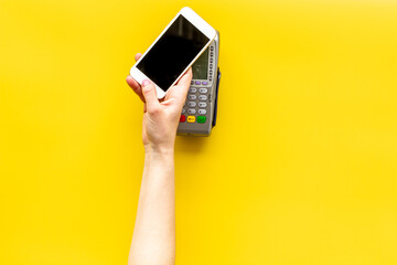 Female hand with mobile phone near POS payment terminal. Payment by mobile pay