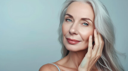 close-up portrait of an elegant senior woman with gray hair, gently touching her face and smiling subtly, set against a neutral background, suggesting a skincare or beauty theme.