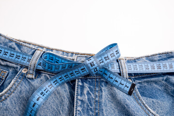 Measure the tape with light blue jeans on a colored background. Diet. Healthy lifestyle and weight loss concept. Empty space for text