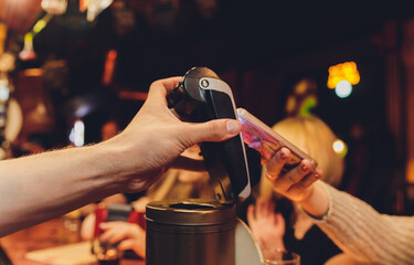 Woman making payment using NFC technology at the shop, cafe or bar.