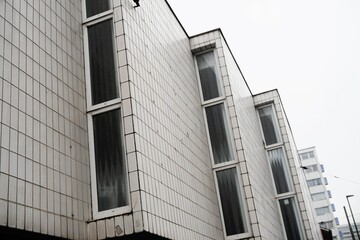 Weiße Klinkerfassade mit drei Vorbauen mit Fenstern von Tanzschule vor weißem Himmel in Stadt am Mittag im Winter