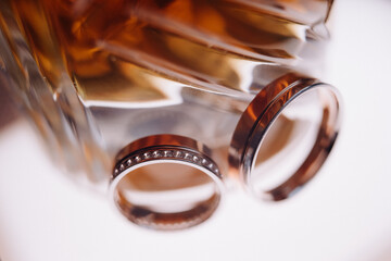 Wedding rings together with the engagement close-up lie on a glass surface
