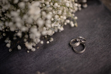Obraz na płótnie Canvas Wedding rings together with the engagement ring close-up lie on a gray textile surface