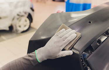 Auto mechanic preparing the car for paint job by applying polish with the power buffer machine
