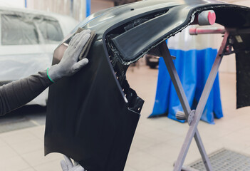 Auto mechanic preparing the car for paint job by applying polish with the power buffer machine