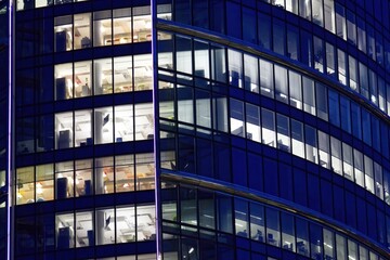 Fragment of the glass facade of a modern corporate building at night. Modern glass office in...