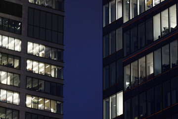 Fragment of the glass facade of a modern corporate building at night. Modern glass office in city.Pattern of office buildings windows illuminated at night.