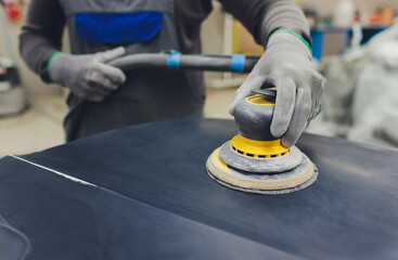 Auto mechanic preparing the car for paint job by applying polish with the power buffer machine