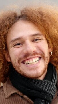 Alternative young man with curly hair smiling at camera