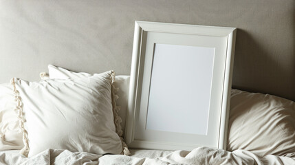 White frame mockup picture on bed close-up, detail of room interior with blank poster and pillows. Concept of home design, bedroom, linen, mock up.