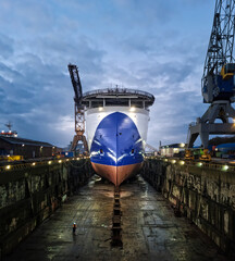 Large seismic offshore research ship in dry dock after painting hull surrounded with industrial...