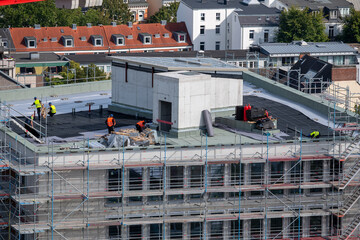 Birdseye view of roofer waterproofing the flat roof of a commercial building..