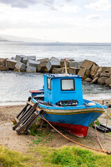 Small fishing boat stopped on the beach of the Strait of Messina between the towns of Ganzirri and Capo Peloro in the municipality of Messina. Area affected by the construction of the Bridge .