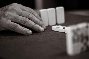 Close-up of an unrecognizable elderly person with wrinkles and veins playing a game of dominoes