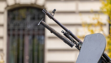 Gun barrel closeup detail, weapon mounted on top of an armored military vehicle in the city seen...