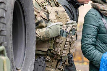 Fully equipped soldier with a generic tactical vest holding many spare magazines, ammunition, detail closeup. Anonymous professional infantry soldier fighter with full equipment on the street, warfare