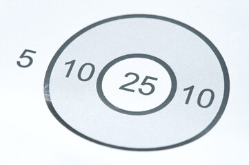 Close-up of a simple white printed paper shooting target with marked circles and scoring numbers of points used for precision weapon shooting practice. Archery, guns, darts, aim accuracy training