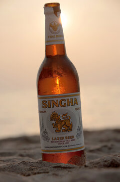 Kho Lanta, Thailand - February 11, 2011: Bottle of Singha beer glistening against a sunset on a beach in the sand