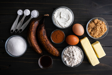 Banana Cinnamon Muffin Ingredients on a Dark Wooden Table: Over-ripe bananas, ground cinnamon, and other breakfast muffin ingredients on a table