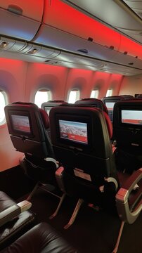 A photo showing a row of unoccupied airplane seats, each with individual LCD screens in the cabin.