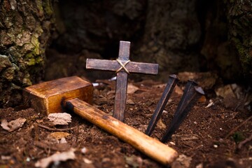 Christian wooden cross and hammer with metal Nails on ground