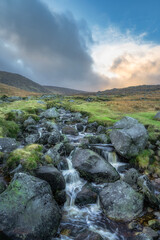 Stream with small waterfalls and cascades in Glendalough at sunset. Hiking in beautiful autumn Wicklow Mountains, Ireland