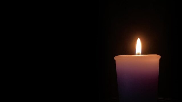 Candle and flame against a black background