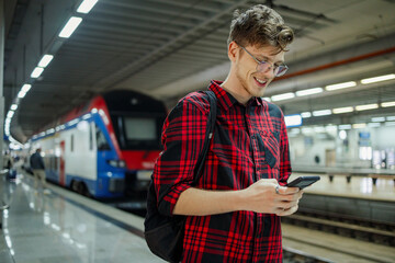 Man commuting to work or a school by a train or a subway while using a phone