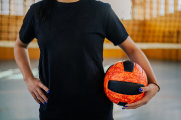 Cropped picture of a volleyball player holding a ball on court.