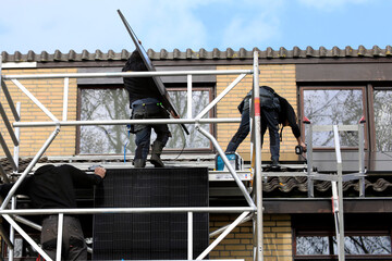 Service engineers installing solar panels on a roof of a residential house